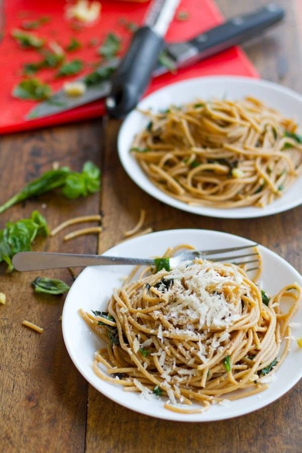 Garlic butter spaghetti with herbs on two white plates.