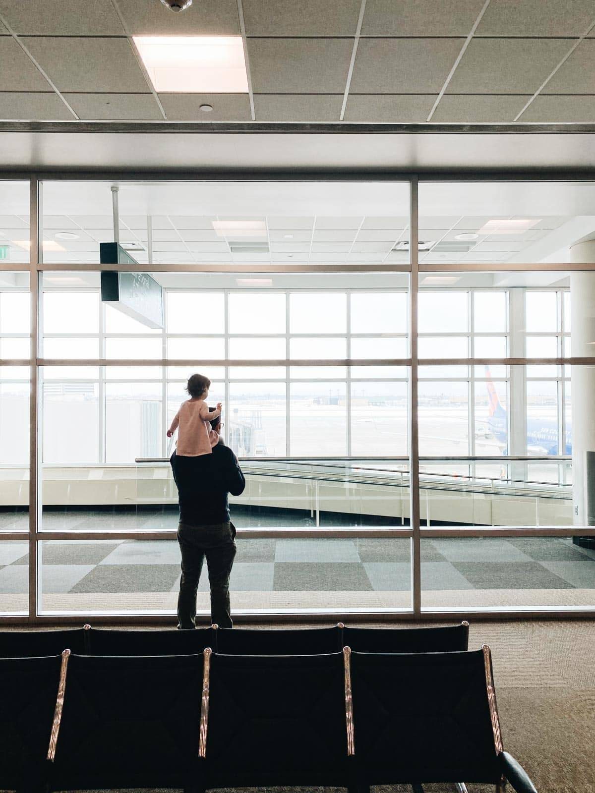 A child sitting on a man's shoulders in an airport.
