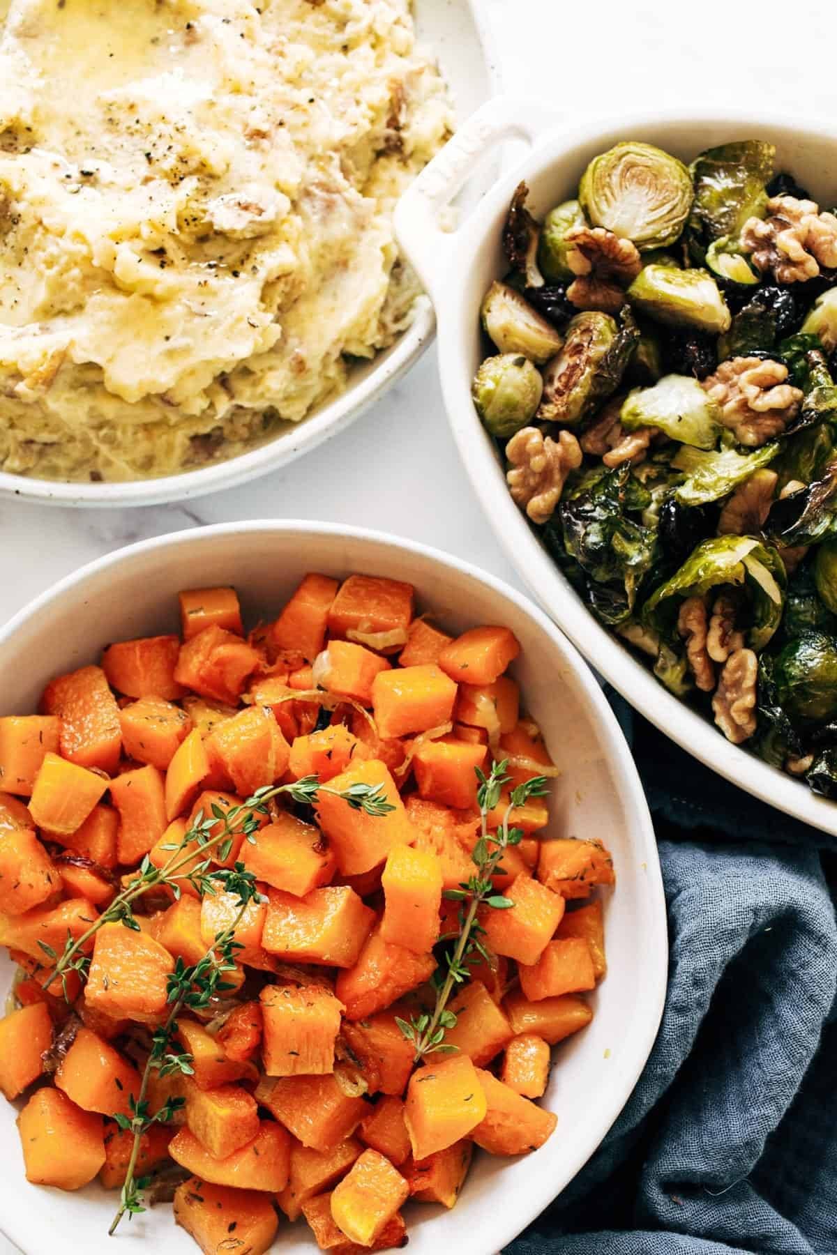 Mashed potatoes, brussels sprouts, and herbed squash in bowls.