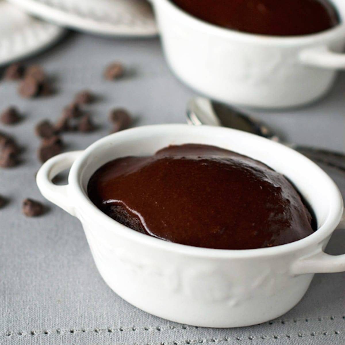 Chocolate cherry fudge cake topped with homemade fudge frosting in a white dish.